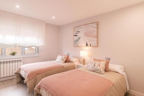 una camera da letto con due letti e una finestra di Apartamento en Llanes a Llanes