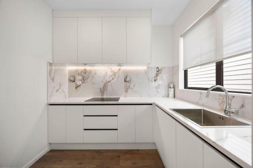 a white kitchen with white cabinets and a sink at Greenstead Retreat 11 beds, 8 bedrooms, 5 baths in Auckland