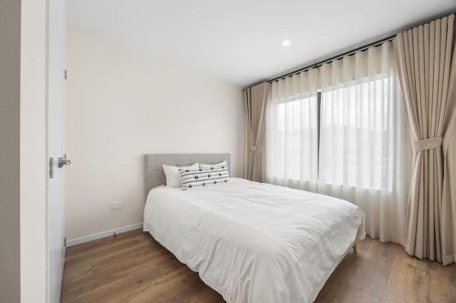 a white bedroom with a large bed and a window at Greenstead Retreat 11 beds, 8 bedrooms, 5 baths in Auckland