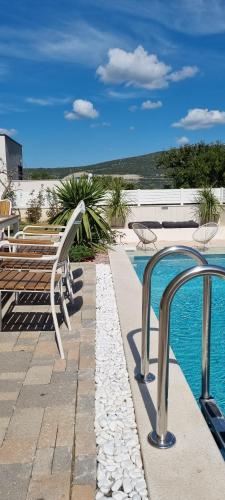 a swimming pool with a bench next to a swimming pool at Villa Korta Regina in Ston