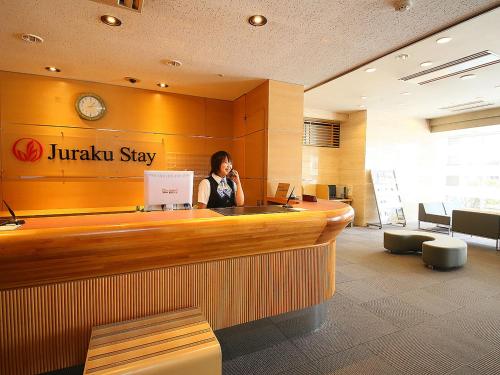 a woman talking on a cell phone at a hotel lobby at Juraku Stay Niigata in Niigata