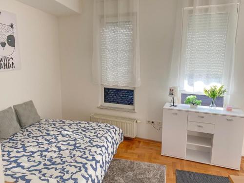 a bedroom with a bed and a sink and two windows at Studio City apartment Sweet Panda in Zagreb