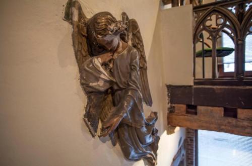 a bronze angel statue on a wall next to a window at Living History - Drie Koningen in Antwerp