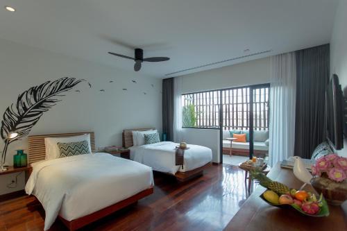 a bedroom with two beds and a living room at The Aviary Hotel in Siem Reap