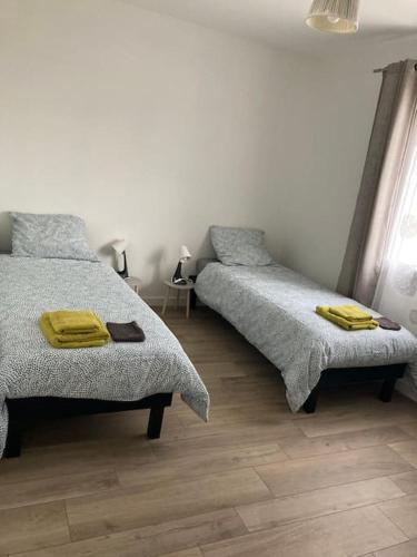 - une chambre avec 2 lits et des serviettes jaunes dans l'établissement Maison Chaleureuse à 10 min du Futuroscope, à Jaunay-Clan