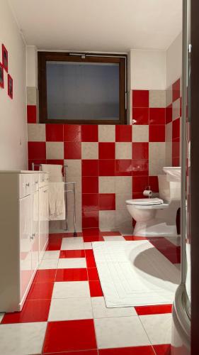 a red and white bathroom with a toilet and sink at 2 bedroom apt near Como lake in Morbio Inferiore