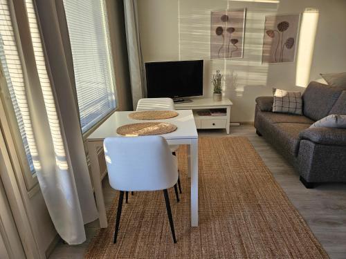 a living room with a white table and a chair at City Apartment with Lakeview in Iisalmi in Iisalmi