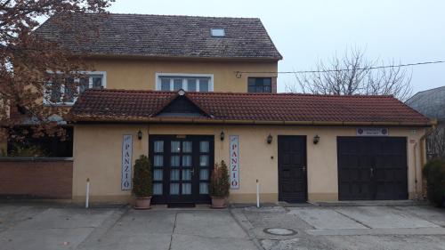 a house with two garage doors in a driveway at Zeke Szálláshely in Vác