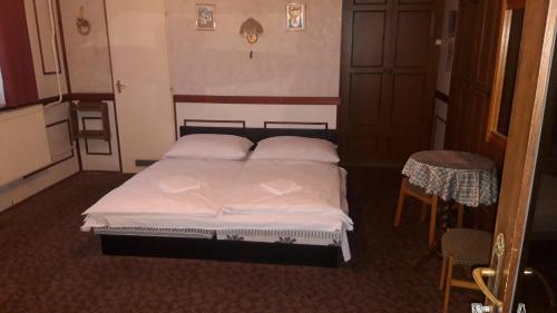 a bedroom with a bed with two pillows and a table at Zeke Szálláshely in Vác