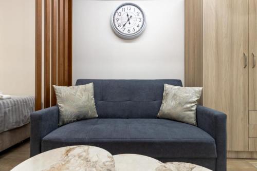 a blue couch in a living room with a clock on the wall at Cozy DownTown Apartment in Xanthi