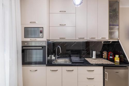 a kitchen with white cabinets and a sink at Cozy DownTown Apartment in Xanthi