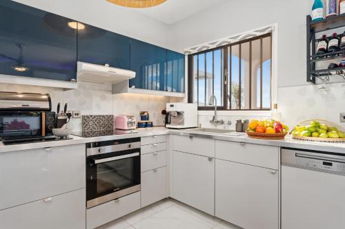 a kitchen with white cabinets and a bowl of fruit at Villa Jasmine Sirens Beach, CYPR - Dom na Cyprze in Ayia Napa