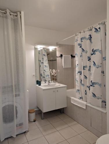 une salle de bain avec un lavabo et un rideau de douche dans l'établissement Chic appartement à 5 minutes de bus de Disneyland, à Serris