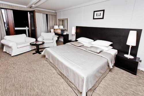 a bedroom with a large bed and two white chairs at Soho Beach Hotel in Krasnogorsk