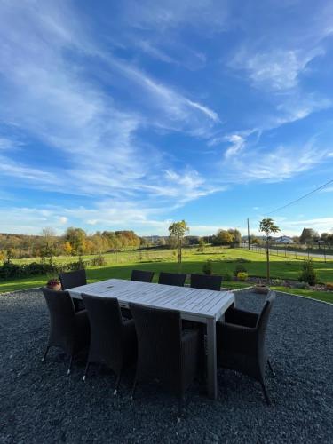 a table and chairs with a view of a field at Le Daguet in Florenville
