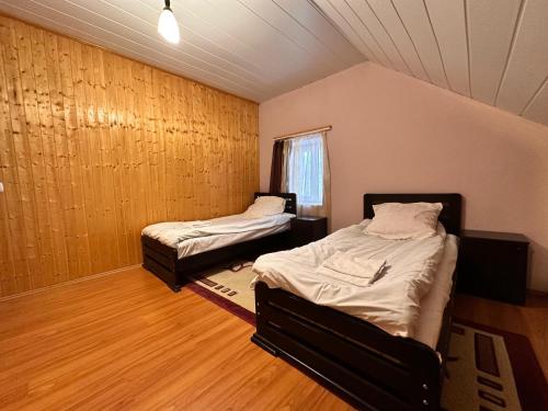 two beds in a room with wood floors and a window at Family Hotel Parnas 2250 in Gudauri