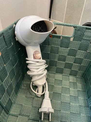 Un sèche-cheveux blanc est suspendu à un mur. dans l'établissement Studio cosy 10min de Paris & CDG, à Drancy