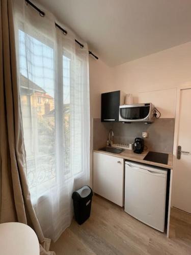 une petite cuisine avec une grande fenêtre et un comptoir dans l'établissement Studio cosy 10min de Paris & CDG, à Drancy