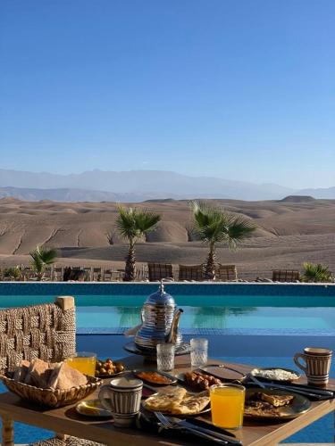 a table with food on it next to a pool at Agafay Desert Stay in Guertsdar