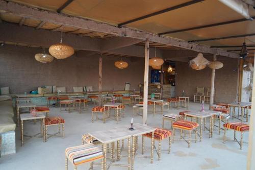a dining room with tables and chairs and lights at Agafay Desert Stay in Guertsdar