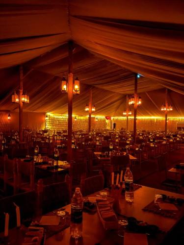 a large tent with tables and chairs and lights at Agafay Desert Stay in Guertsdar