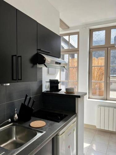 une cuisine avec un évier et une cuisinière dans l'établissement Carré d or de Rouen vue sur la cathédrale, à Rouen