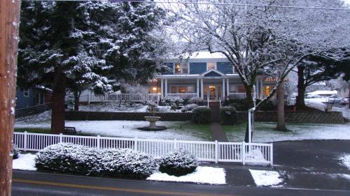 a house with a white fence in the snow at Terraluna Inn in Roseburg