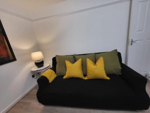 a black couch with four yellow pillows on it at Cosy 2 Bedroom Apartment in Stifford