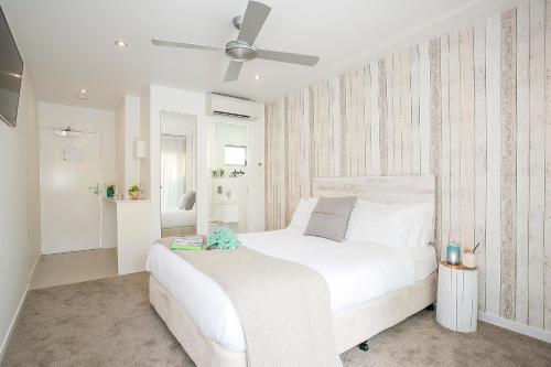 a bedroom with a white bed with a ceiling fan at 10 Hastings Street Motel in Noosa Heads