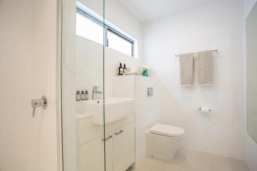 a white bathroom with a toilet and a sink at 10 Hastings Street Motel in Noosa Heads