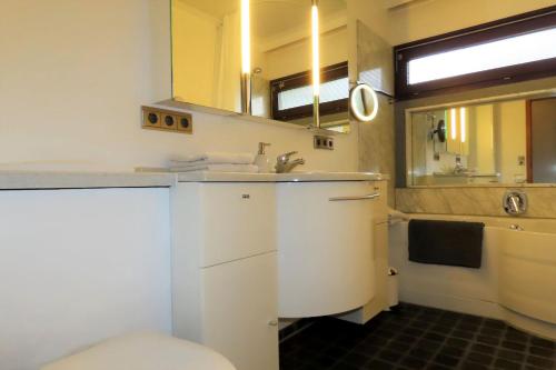 Un baño con lavabo, inodoro y espejo. en Droste 17 MBG - Whg A, en Meersburg