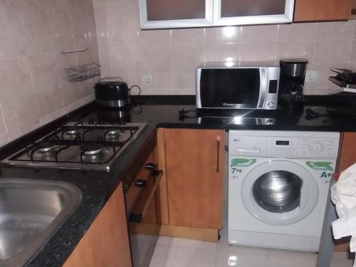 a kitchen with a microwave and a washing machine at Summerstep Guesthouse in São Tomé