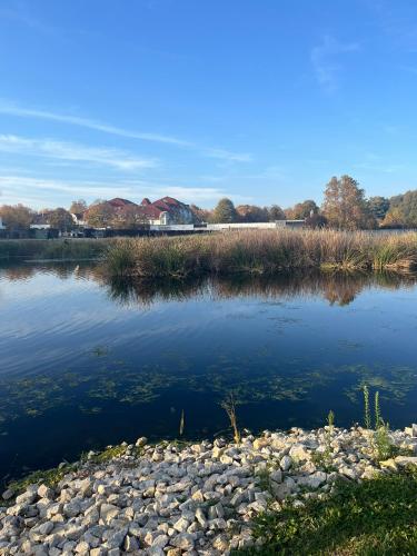 a body of water with rocks and houses in the background at Prestige Zalakaros Apartman in Zalakaros