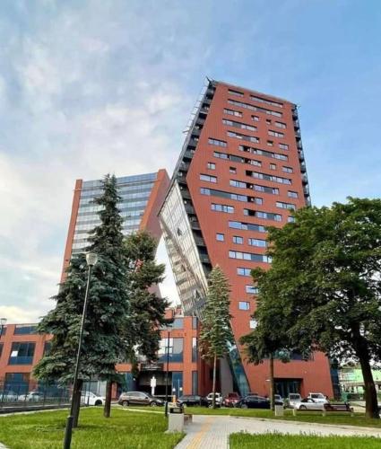 a tall red building with trees in front of it at Panoramic city center apartment in Klaipėda