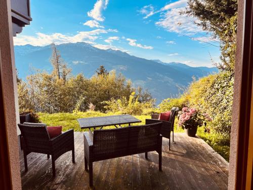 a table and chairs on a deck with a view of mountains at Sonnalm Panoramablick Garten Sauna in Rohrberg