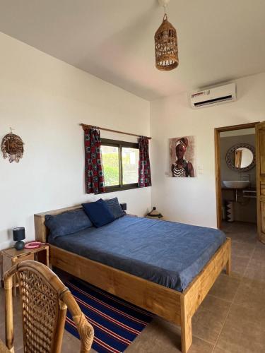 a bedroom with a bed with blue sheets and a window at Villa Vista in Toubab Dialaw