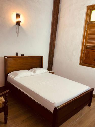 a bedroom with a bed with white sheets and a window at Casa Encanto Buga in Buga