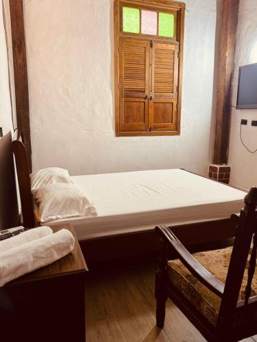 a bed in a room with a window and a chair at Casa Encanto Buga in Buga