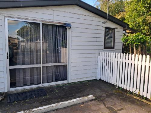 a white house with a fence and a window at Sweet Guesthouse in Waitara