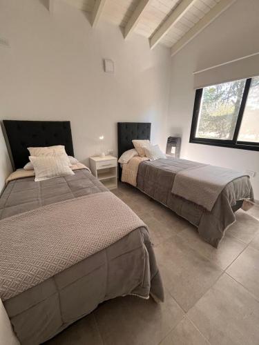 two beds in a white room with two beds sidx sidx sidx at Sierras VGB Centro in Villa General Belgrano