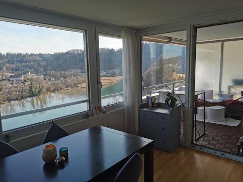 a living room with a table and large windows at Beautiful view on the river Aare in Hinterkappelen