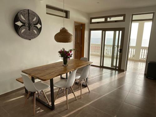 a dining room with a wooden table and white chairs at Villa Vista in Toubab Dialaw