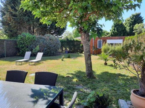 a garden with chairs and a table and a tree at VILLA DE PLAIN PIED ET STUDIO CLIMATISES, AU CALME, 6 PERSONNES MAXIMUM A 7mn DU GOLF ET DE LA PLAGE in Seignosse