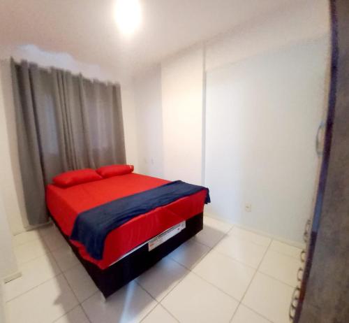 a bedroom with a red bed in a white room at Apto Vista do Pôr do Sol SUN7 in Ilhéus