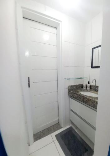a bathroom with a white door and a sink at Apto Vista do Pôr do Sol SUN7 in Ilhéus