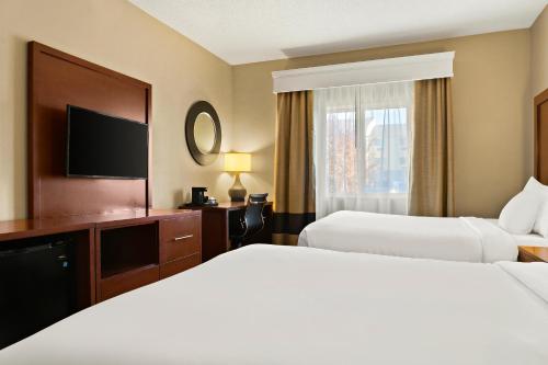 a hotel room with two beds and a television at Comfort Suites in Saginaw