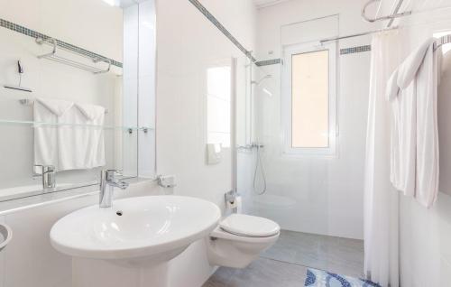 a white bathroom with a toilet and a sink at Apartments Funtana with pool in Funtana