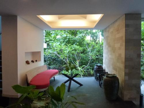 a living room with a red bench and a large window at Allia Residence in Nusa Dua