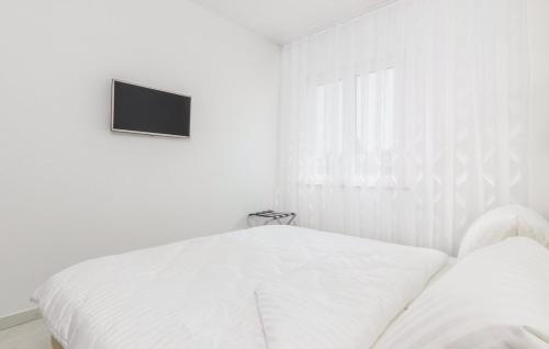 a white bedroom with a bed and a tv on the wall at Apartments Funtana with pool in Funtana