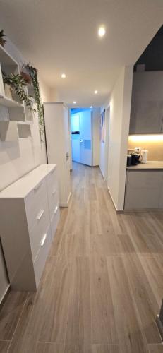 a kitchen with white cabinets and a hard wood floor at Jungle Sunshine Apartment in Alessandria